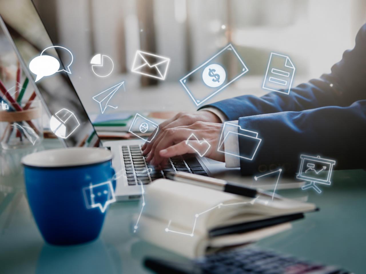 Business hands on a laptop with digital service icons floating above